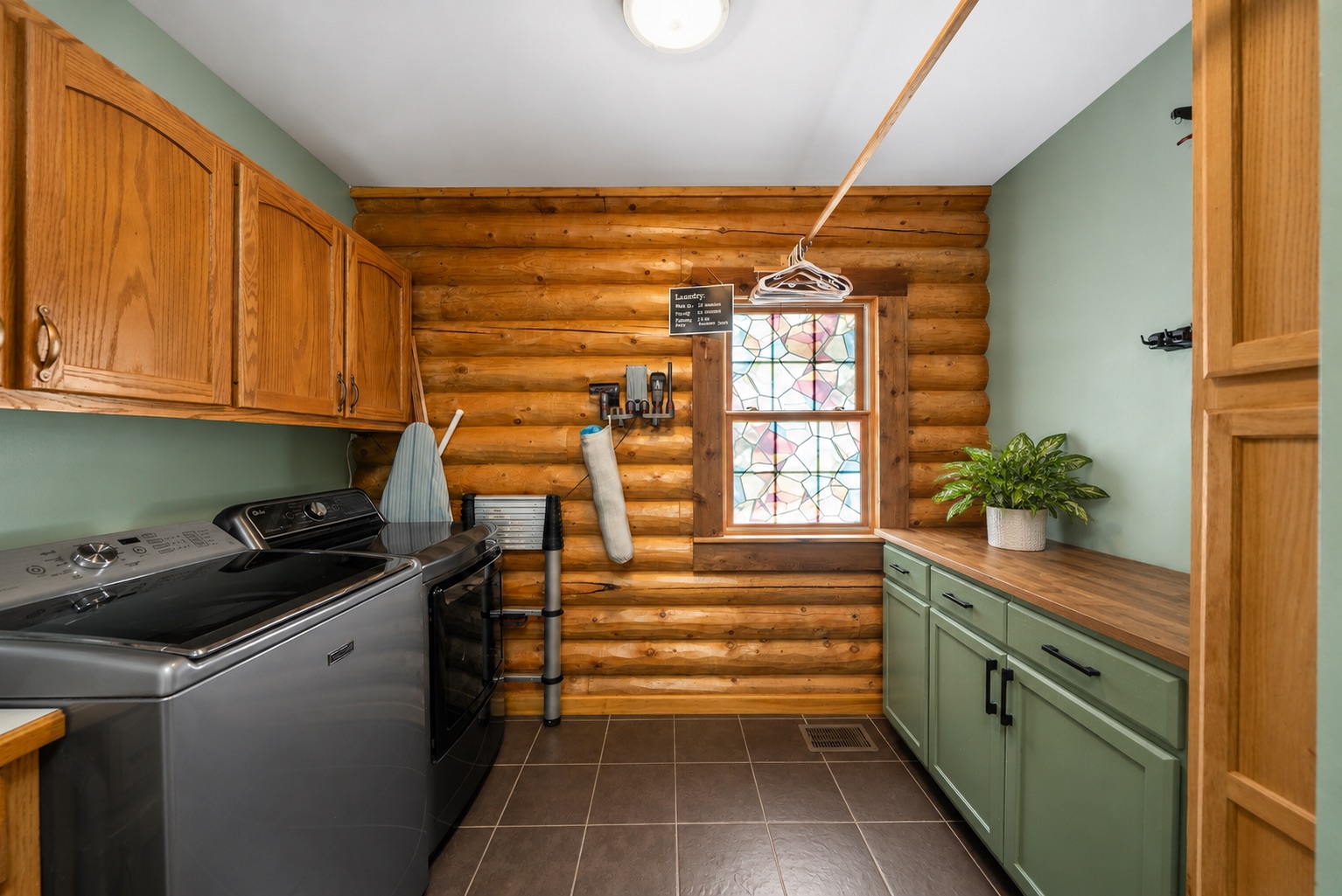 Laundry room with stained glass window and sage cabinetry